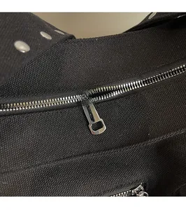 Detailed macro shot of silver metal zipper and smooth hardware on black canvas shoulder bag