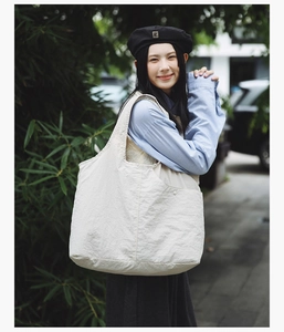 Détail d'un sac cabas crème minimaliste avec poche latérale boutonné sur un mannequin