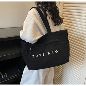Détail du sac cabas en velours côtelé noir montrant la texture et l'inscription blanche