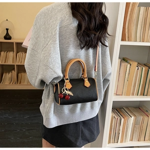 Mini Boston bag in black pebble grain with brown trim and cherry charm on model