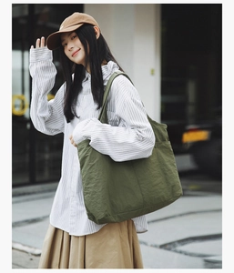 Détail d'un sac fourre-tout en nylon vert armée porté avec une chemise rayée décontractée