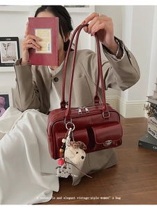 Close-up of a vintage red shoulder bag with silver hardware and plush dog charm accessory