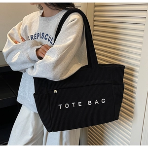 Détail d'un sac cabas en velours côtelé noir avec broderie blanche dans un cadre intérieur