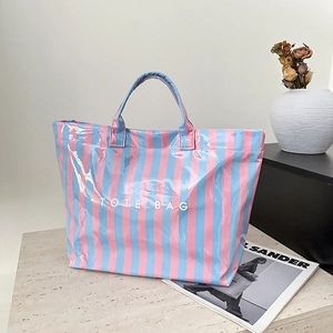 Détail d'un cabas rayé rose et bleu brillant avec l'inscription TOTE BAG blanche stylée