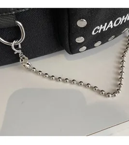 Macro detail of black canvas bag with silver ball chain and metal stud decorations