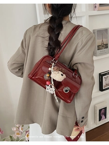 Detail view of deep red vintage shoulder bag with plush bear charm and metallic hardware