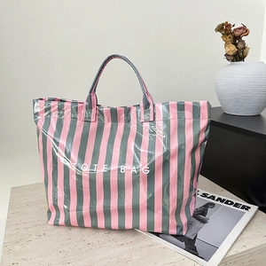 Gros plan détaillé du sac cabas rayé rose et gris posé sur une surface en marbre
