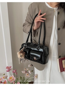 Detail of vintage black leather Boston bag with dual pockets and plush bear charm