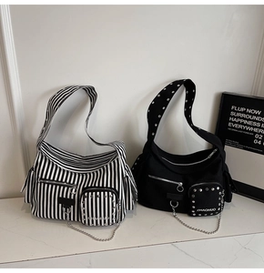 Detail view of canvas rivet shoulder bag with striped design and metallic punk accents