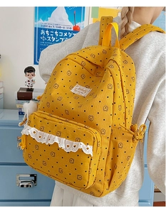 Detailed view of yellow corduroy backpack with brown bear patterns and white lace trim
