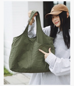 Détail de la texture d'un sac cabas en nylon vert olive avec poches latérales et boutons