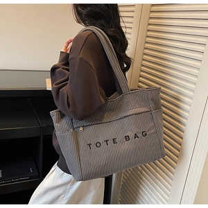 Gros plan sur le sac fourre-tout en velours côtelé gris foncé avec poche zippée