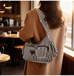Close-up of canvas shoulder bag with silver studs, metal chains and striped pattern