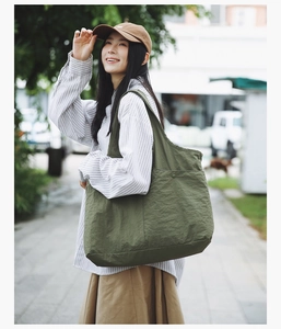 Détail de la poche latérale à bouton-pression sur un grand sac fourre-tout en nylon vert olive