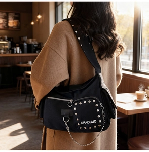 Detail showing black canvas bag with silver rivets and metallic chain strap