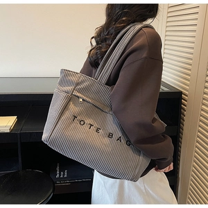 Vue détaillée du sac cabas en velours côtelé gris avec broderie et poche zippée latérale