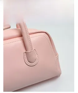 Gros plan du sac bandoulière rose montrant les coutures fines et le cuir grainé doux