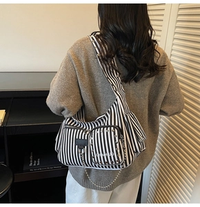 Detailed close-up of a striped canvas crossbody bag featuring silver rivets and chain straps