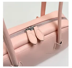 Détail du sac en cuir rose montrant des fermetures éclair métalliques argentées fluides
