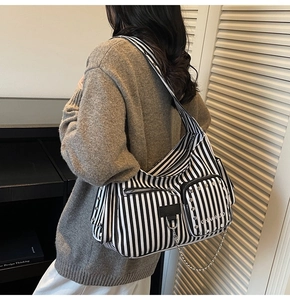 Detail view of black and white striped canvas messenger bag with silver rivets and metal chain