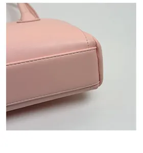 Détail d'un sac à bandoulière en cuir rose montrant le fond renforcé et la couture précise