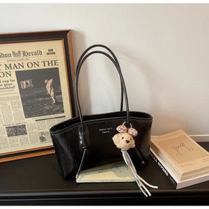 Borsa tote nera minimalista effetto lucido con ciondolo a orsetto e nappe eleganti