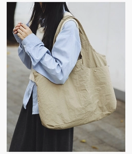 Détail du sac cabas en nylon kaki montrant la poche latérale et les rivets en métal