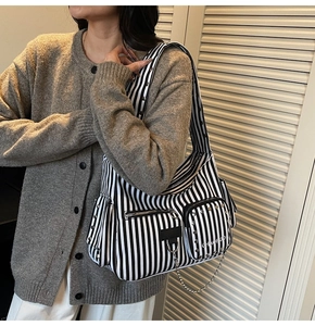 Detail view of black and white striped biker bag with silver metal studs and chain strap