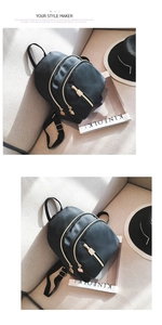 Detail of black nylon backpack featuring golden metal zippers and multi-layer storage compartments