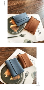 Close-up of minimalist matte leather envelopes in grey-blue and caramel on a wooden desk