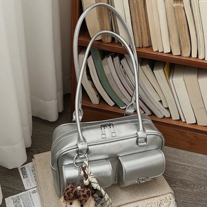 Silver metallic shoulder bag with double pockets and leopard bow bear charm on beige mat