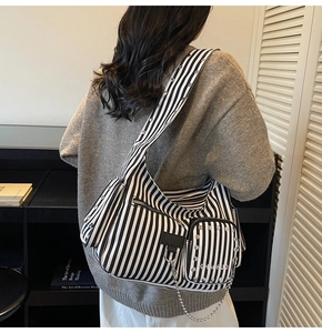 Detail of black and white striped tote with silver studs and metal chain accessory
