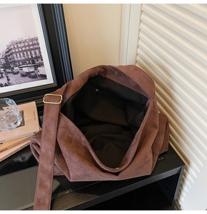 Detail view of dark brown suede tote bag featuring magnetic closure and inner zip pocket