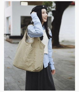 Détail d'un sac cabas en nylon kaki avec texture plissée et poche latérale en décor urbain