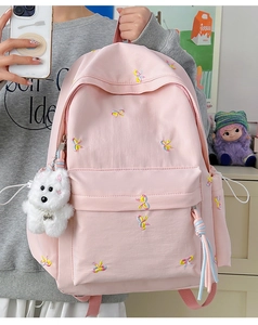 Detail of pink backpack featuring colorful butterfly embroidery and white plush dog charm