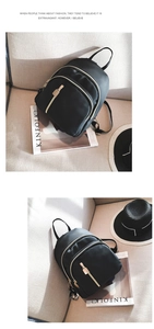Detail of classic black nylon backpack with elegant gold metal zippers on a sofa