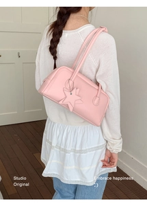 Détail d'un sac porté épaule en cuir rose avec breloque étoile sur un mannequin