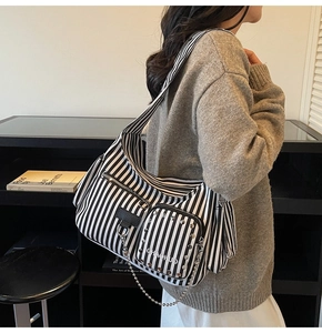Detail of black and white striped canvas crossbody bag with silver studs and chain
