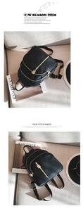 Detail of a black nylon backpack with gold zippers shown on a cozy sofa with props