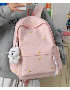 Detailed view of pink school backpack with embroidered bows and plush puppy charm