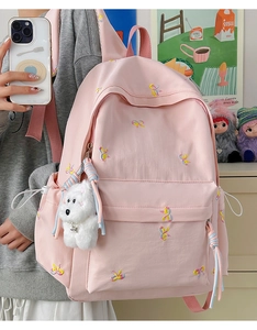 Detail of light pink backpack with butterfly embroidery and plush puppy charm