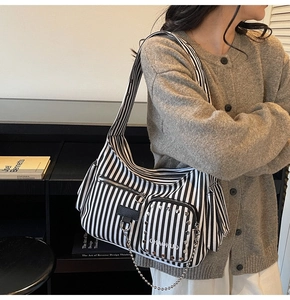 Detail of striped canvas shoulder bag featuring silver rivets and metal ball chain decor