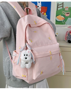 Detailed embroidery of colorful butterflies and cute puppy charm on a pink backpack