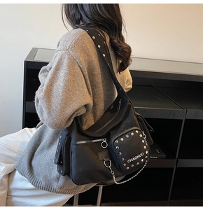 Detail view of black canvas motorcycle bag with silver rivets and metallic chain strap