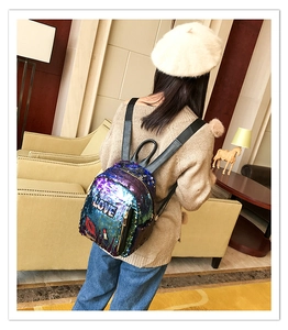 Detail view of mini sequin backpack with LOVE embroidery and lip pattern on a model