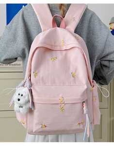 Detailed view of pink school backpack featuring cute butterfly embroidery and dog plush charm
