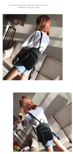 Mini black nylon backpack with gold zippers shown on a model in a bright, sunlit room