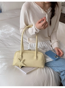 Détail d'un sac à bandoulière crème avec pendentif en forme d'étoile et fermeture éclair
