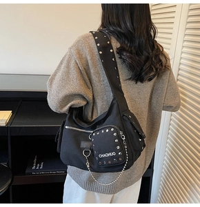 Detailed view of black canvas motorcycle bag with silver rivets and metal chain accents