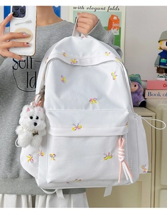 Detail of white backpack featuring cute bow embroidery and a plush puppy charm attachment